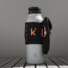Thermos bottle with black bag and pink carabiner on a wooden surface against a brown background